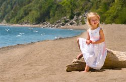 Outdoor portrait of a young Girl sitting on a large piece of Dri