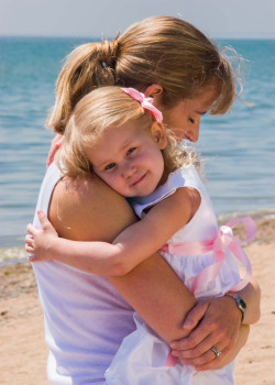 Outdoor Portrait of a mother standing on a sandy beach, looking