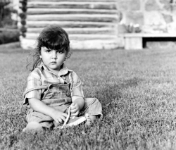 Casual outdoor portrait of a young girl wearing denim coveralls,