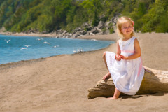 Outdoor portrait of a young Girl sitting on a large piece of Dri