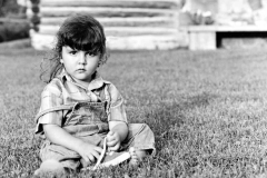 Casual outdoor portrait of a young girl wearing denim coveralls,