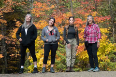 Casual outdoor portrait of four women standing side by side at t