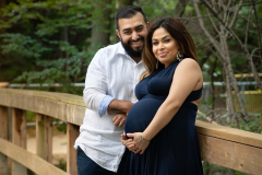 Outdoor portair of an expectant mother and father leaning on the
