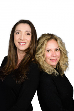 Waist hight photograph of two women standing back-to-back to be