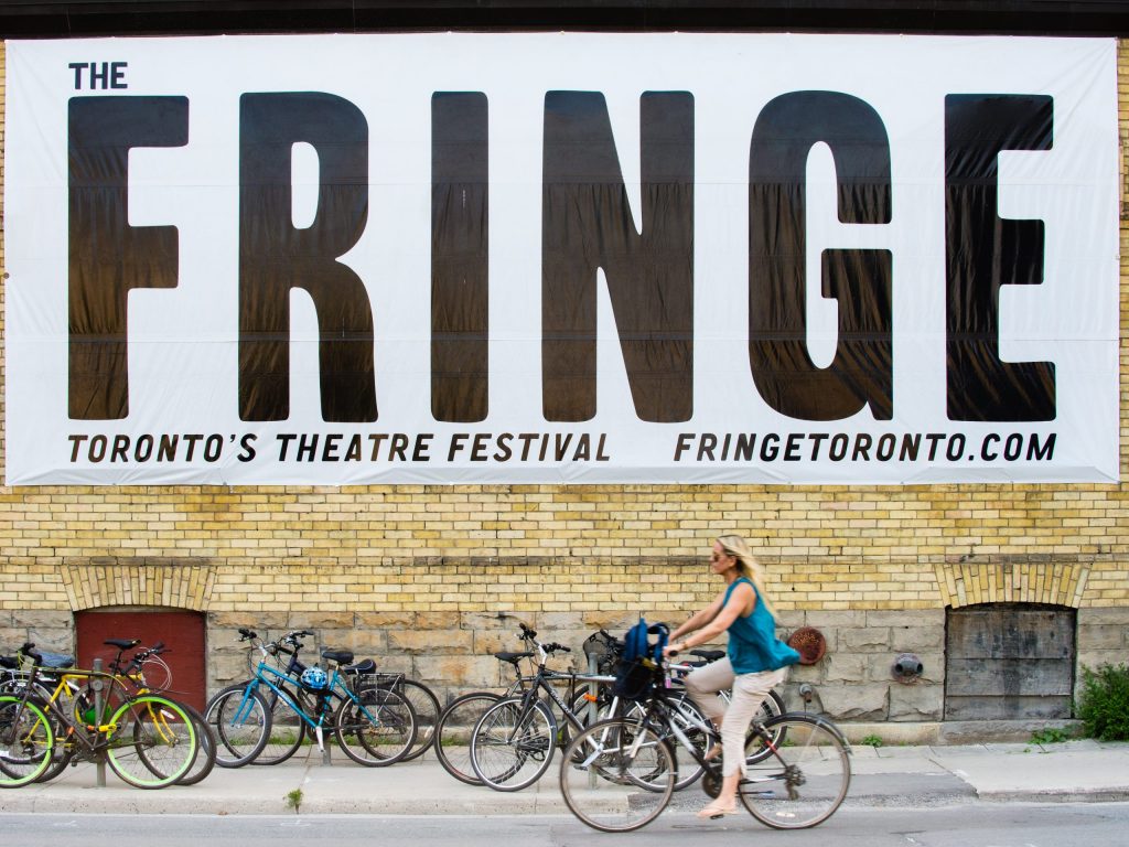 MHP-150712-7115 Photo of woman cycling past Toronto Fringe Theatre Festival banner